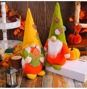 Detail of plush Thanksgiving gnomes with autumn elements like corn and acorns on wood