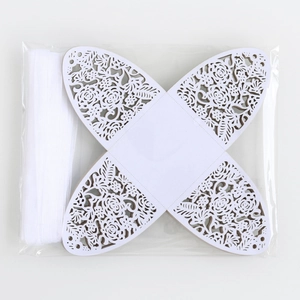 Flat lay of laser-cut hollow rose candy boxes in white with matching ribbon in packaging
