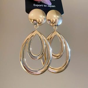 Détail de grandes boucles d'oreilles dorées double goutte évidée avec fini brillant