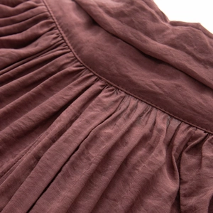 Macro shot of dark reddish-brown sheer blouse with detailed pleats and precise stitching