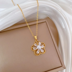 Detail of gold flower pendant necklace featuring central pearl and sparkling zircon stones