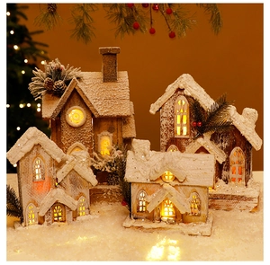Close-up of lighted Christmas wooden houses with artificial snow and warm LED glow