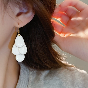 Detail of white layered teardrop earrings with gold hooks on a model for an elegant look