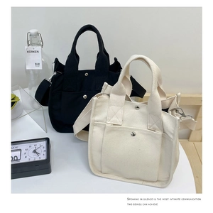 Detail of multi-pocket canvas crossbody bags showing thick fabric and strap hardware