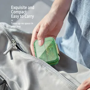 Green transparent weekly pill organizer being placed into a gray zipper bag