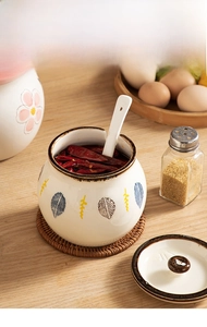 Ceramic seasoning jar with spoon and woven base showing chili oil storage
