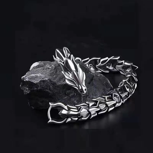 Silver dragon-shaped punk bracelet with dragon scale texture on a dark stone background
