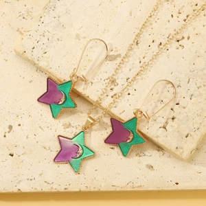 Close-up of gold star jewelry set with purple and green enamel and moon patterns