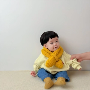 Close-up of bright yellow chunky knit scarf for babies with a cross-style fit