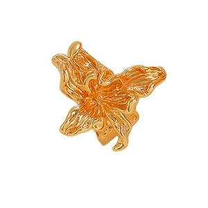 Dettaglio anello a fiore dorato con pieghe irregolari e texture in metallo fuso 3D