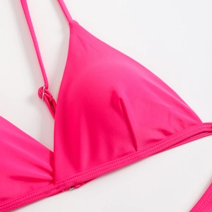 Detailed close-up of a bright pink bikini top with adjustable silver metal buckles