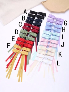Flat lay of silk ribbon bow hair clips in twelve different colors with alphabetic labels