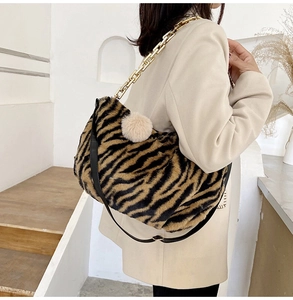 Detail of tiger pattern plush tote bag with gold chain strap and decorative pompom charm
