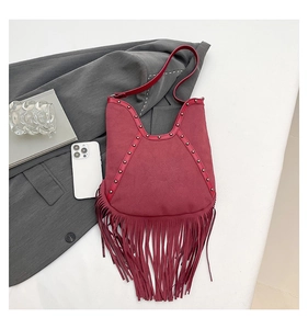 Detail of burgundy suede tote bag featuring fringe, metal rivets and sun embossed pattern