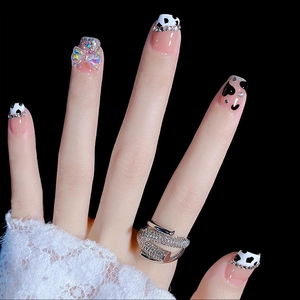 Press-on nails featuring cow print, heart patterns, rhinestones, and 3D bow accents