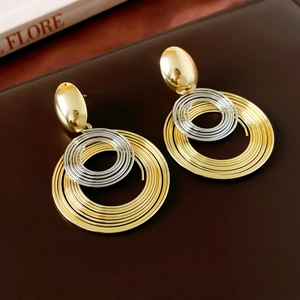 Close-up of mixed metal coiled geometric earrings in gold and silver finish