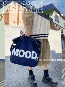 Street style view of a large navy denim tote bag with white MOOD lettering for women