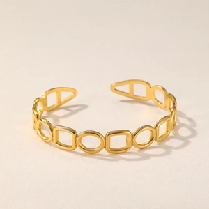Detailed close-up of golden geometric hollow cuff bracelet with circle and square patterns