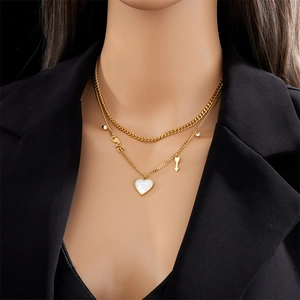 Detail of layered gold necklace with heart, LOVE pendant and arrow charms on a model