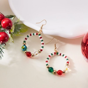 Close-up of Christmas wreath earrings with red, green, and white beads on white background