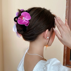 Detailed view of a purple orchid hair claw clip with pearl center on a chic updo