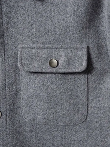 Detail of grey wool texture on men lapel jacket with vintage metal button on chest pocket