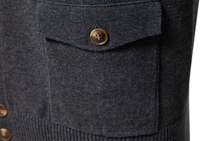 Detail of dark grey knit cardigan showing wood texture brown button and flap pocket