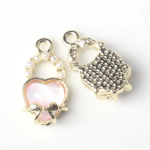 Close-up of pink heart charm with white pearl and golden bow knot for DIY jewelry