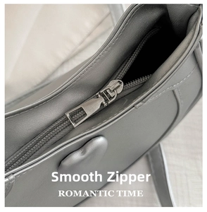 Detail of a smooth metallic zipper closure on a silver crescent-shaped crescent handbag