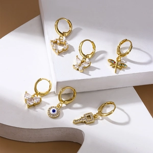 Set of 6 gold earrings with butterfly, heart, and key zircon pendants on white platforms