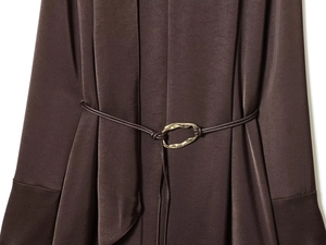 Détail de la robe en soie marron avec une boucle géométrique dorée sur la ceinture de taille