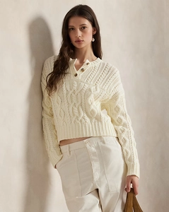 Detail von Zopfmustern und Bernstein-Knöpfen an einem cremefarbenen V-Neck-Pullover