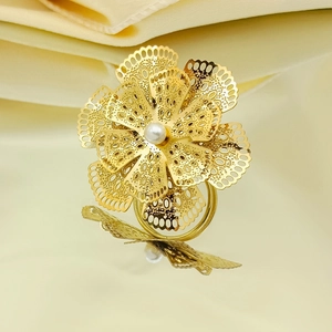 Golden multi-layer hollow floral ring with central pearl on warm reflective background
