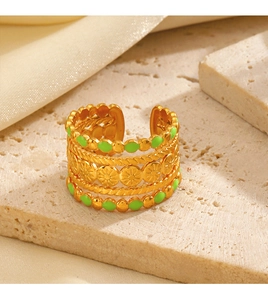 Detail of gold-plated twisted ring with green enamel inlay on a stone surface