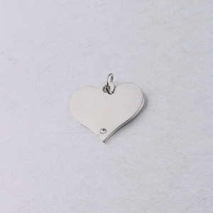 Macro detail of silver heart pendant with sparkling crystal inlay on white texture