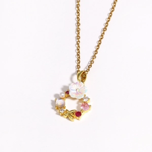 Détail du collier couronne dorée avec fleur blanche oiseau et gemmes colorées