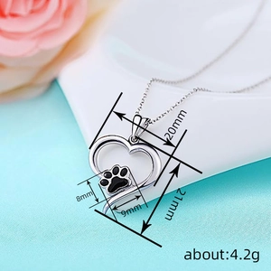 Silver heart necklace with black paw print pendant and dimensions on a soft background