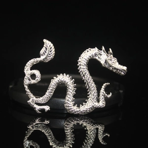 Close-up of silver dragon alloy charm showing detailed scale texture and metallic shine