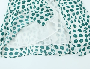 Detail view of white fabric with green polka dots and smooth white inner lining