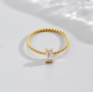 Macro detail of gold twisted rope ring featuring a rectangular zircon in a 4-prong setting