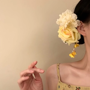 Detail of yellow fabric rose hair clip with pearl beads and elegant tassel on model
