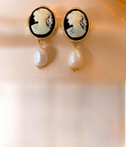 Macro view of vintage cameo pearl earrings with gold plating and steel silver material