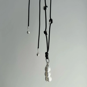 Detail of silver peanut pendant with realistic texture on a black adjustable rope cord