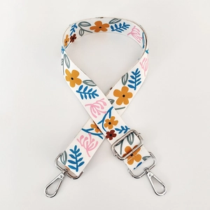 Detail of adjustable bag strap with colorful floral patterns and silver metal swivel hooks