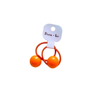 Set of two orange ball elastic hair ties for girls on a white cardboard display