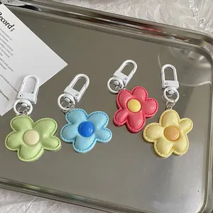Colorful flower keychains in four colors with white carabiner hooks on a metal tray