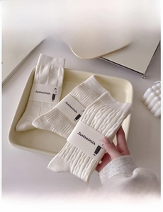 Detailed view of three white cotton mid-tube socks with various textured patterns and packaging
