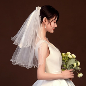 Close-up of a white two-layer short bridal veil featuring a bow and wavy ruffled edges