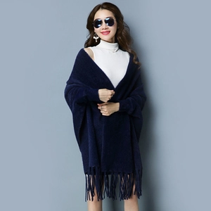 Close-up of navy blue knit poncho cape featuring delicate tassel fringe at the hem