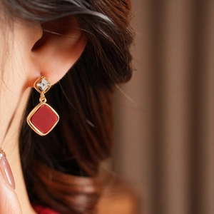 Close-up of 18k gold plated rhombus earrings with red glaze and zircon on a model